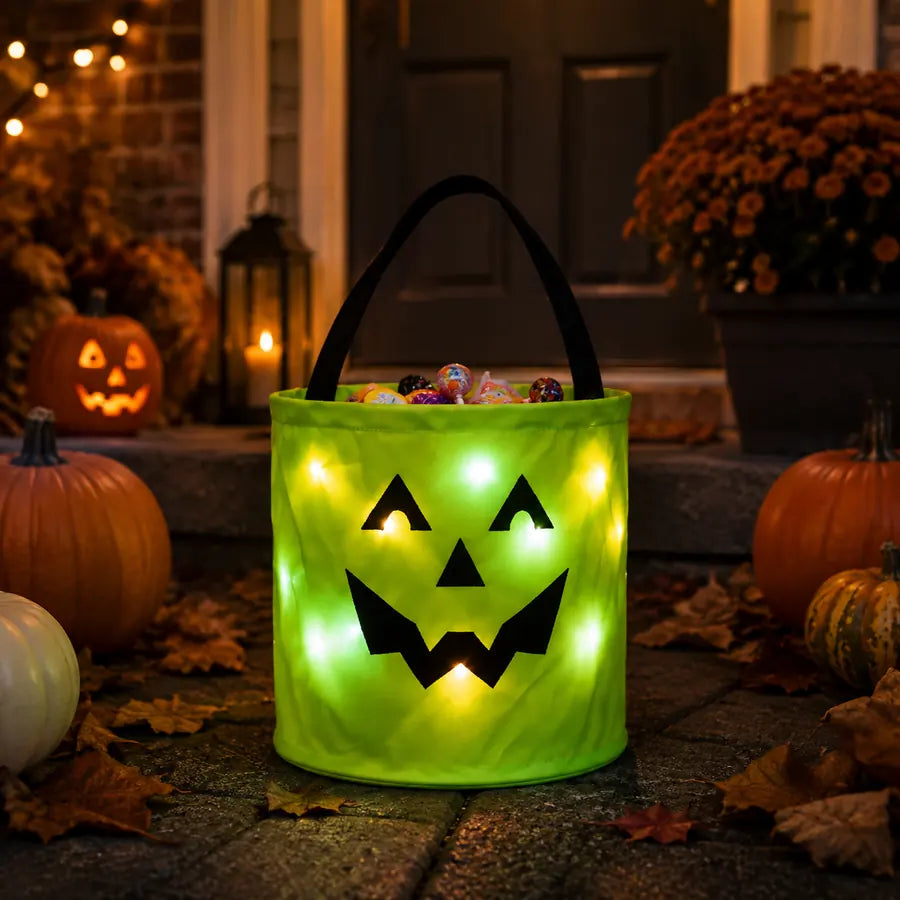 Green BooLume light-up Halloween candy bag glowing on a decorated porch