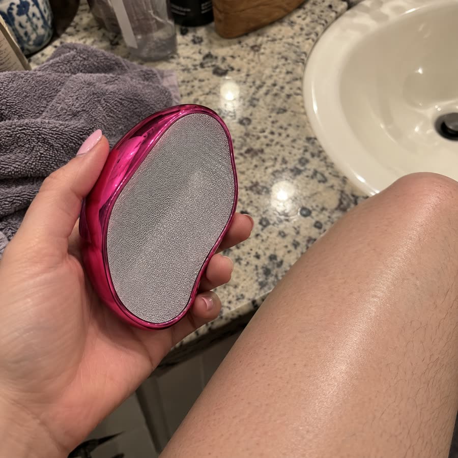 Pink crystal hair eraser held near leg on bathroom counter