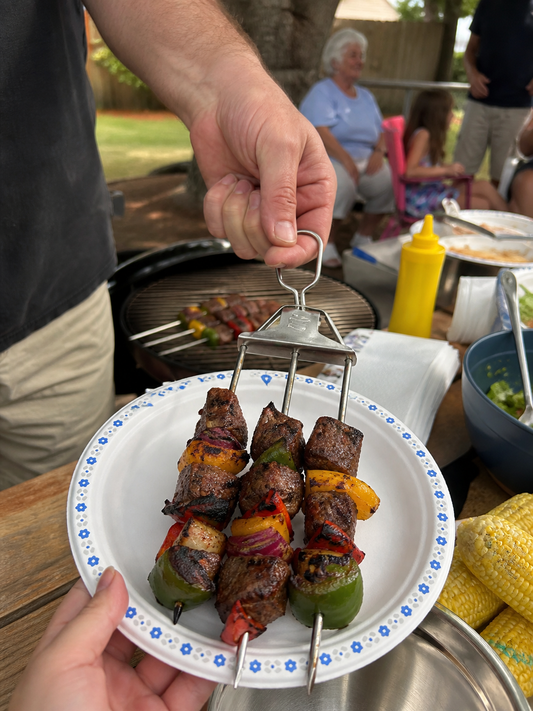 Backyard BBQ serving skewers onto a plate