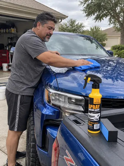 Customer wiping water beads from a blue truck hood