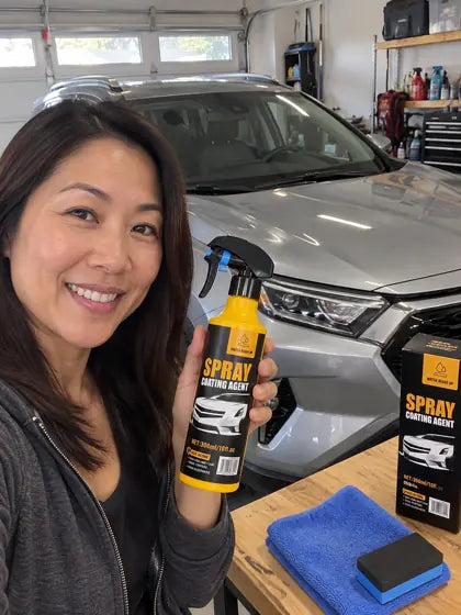 Customer holding car coating spray in front of a silver car
