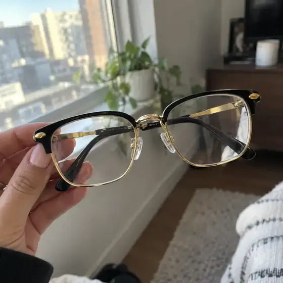 Amanda holding lightweight black and gold glasses near a bright window