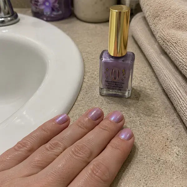 Customer showing lilac nails in a bathroom routine