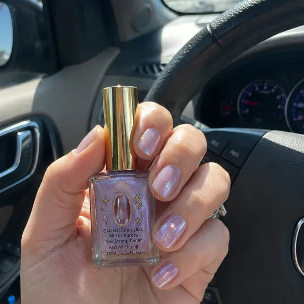Customer holding lilac nail strengthener in a car with glossy nails