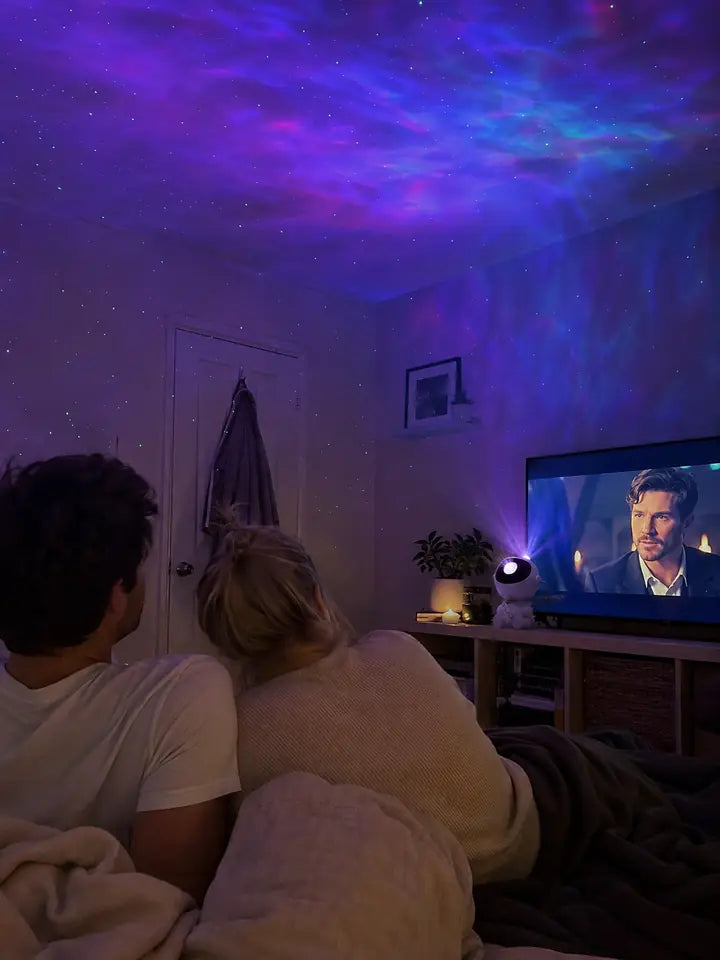 Couple watching TV with galaxy projector lights on the ceiling