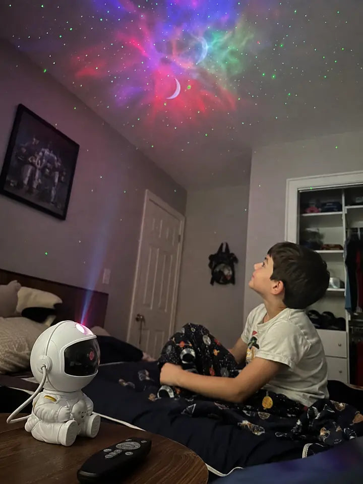 Child sitting in bed watching colorful galaxy projection