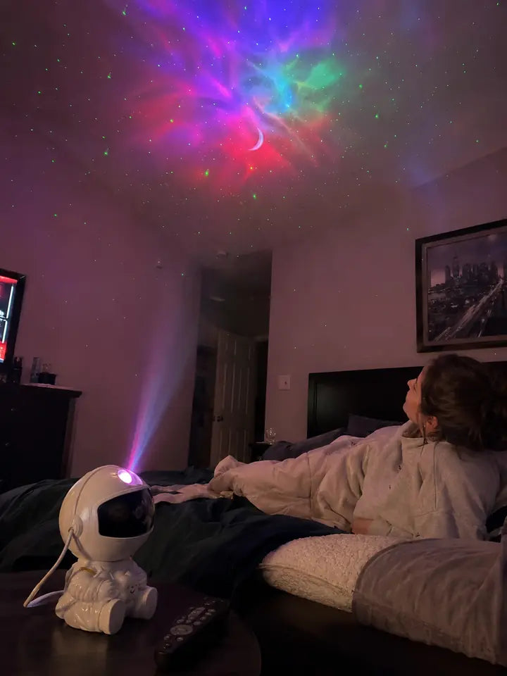 Woman relaxing in bed under moon and galaxy projector lights