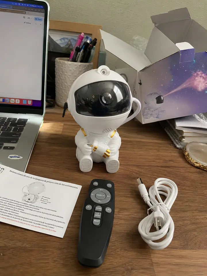 Astronaut projector on a desk with remote, cable, manual, and product box
