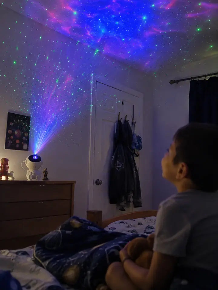 Child watching astronaut projector create colorful stars in a bedroom