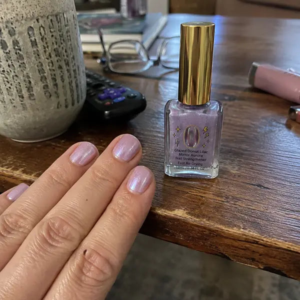 Customer showing lilac nails and bottle on a coffee table