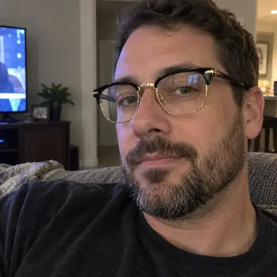 David wearing black and gold blue-light glasses while relaxing at home