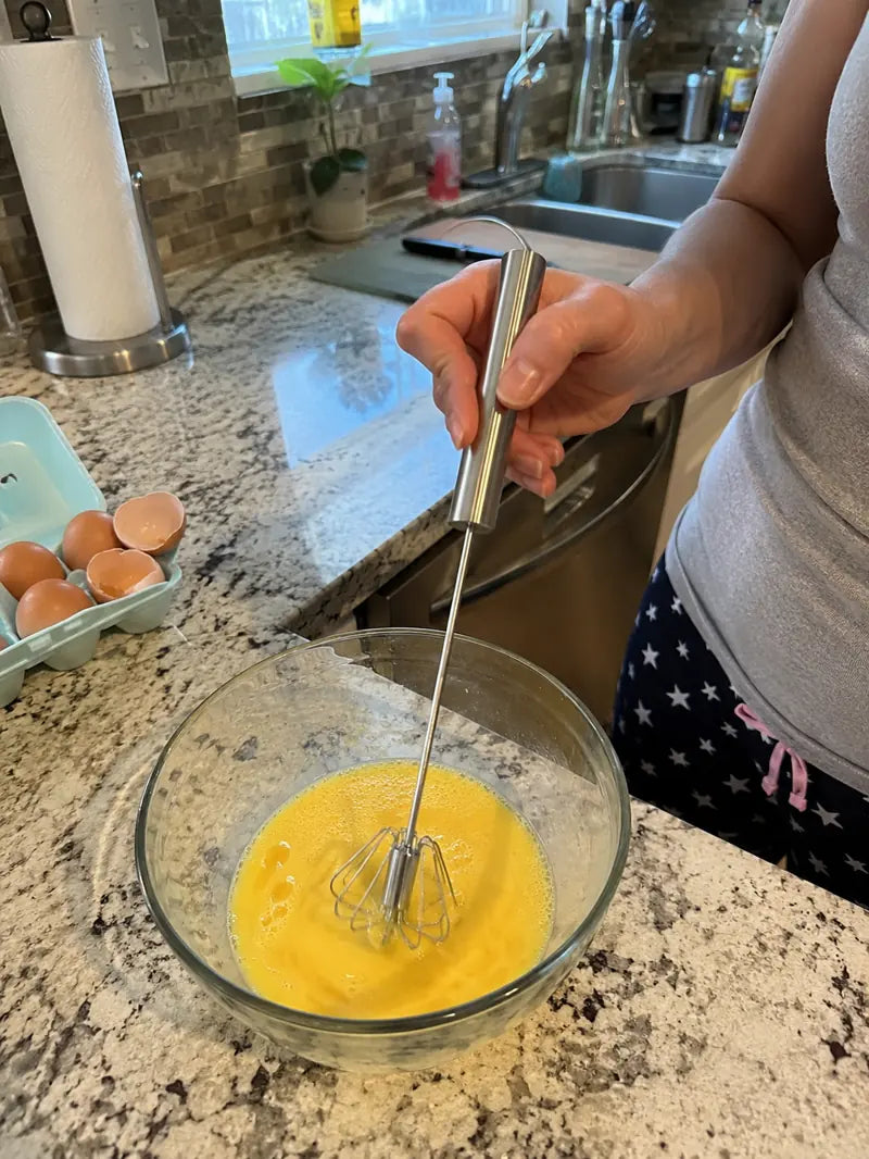 Customer using the hand-push rotary whisk to mix eggs in a kitchen bowl