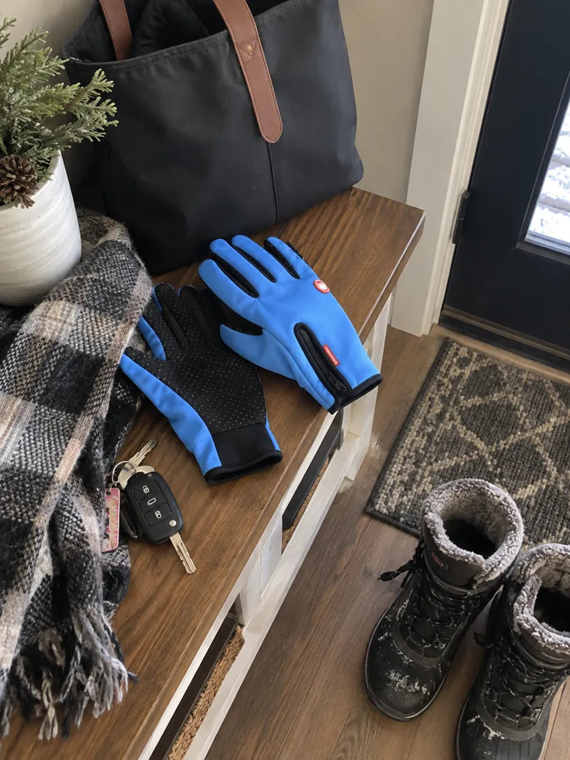 Blue winter gloves on an entryway table beside keys boots and a scarf