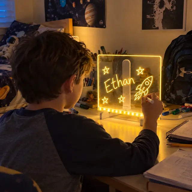 Boy drawing a rocket and his name on a glowing acrylic LED board