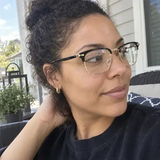 Nicole wearing black and gold glasses outdoors on a porch