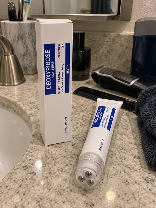 Scalp serum tube and box displayed on a bathroom counter with grooming tools