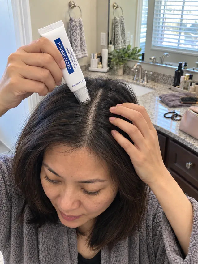 Woman using scalp serum on a center part as part of a daily routine