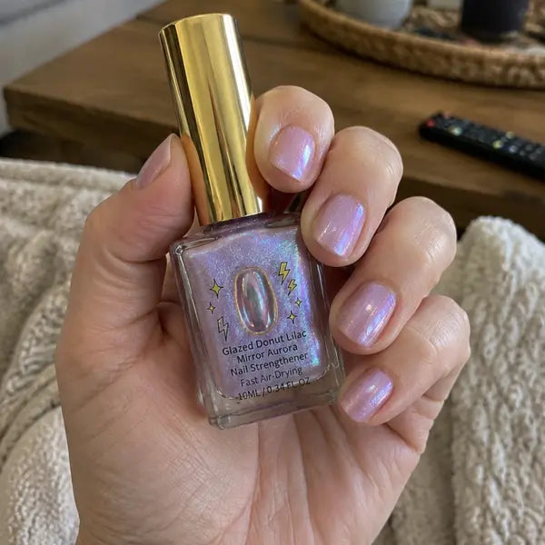 Customer holding lilac nail strengthener while relaxing on a sofa
