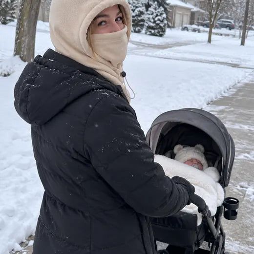 Customer pushing stroller in snow wearing cream fleece hood