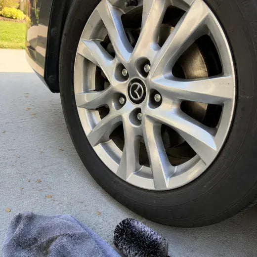 Car wheel cleaned with brush and towel nearby