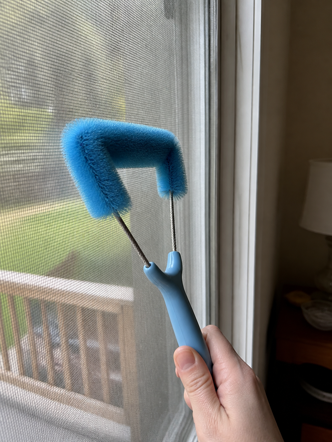 Customer photo of short-handle screen brush cleaning an installed window screen.