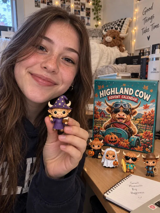 Young woman displaying Highland Cow Halloween calendar figures on a desk