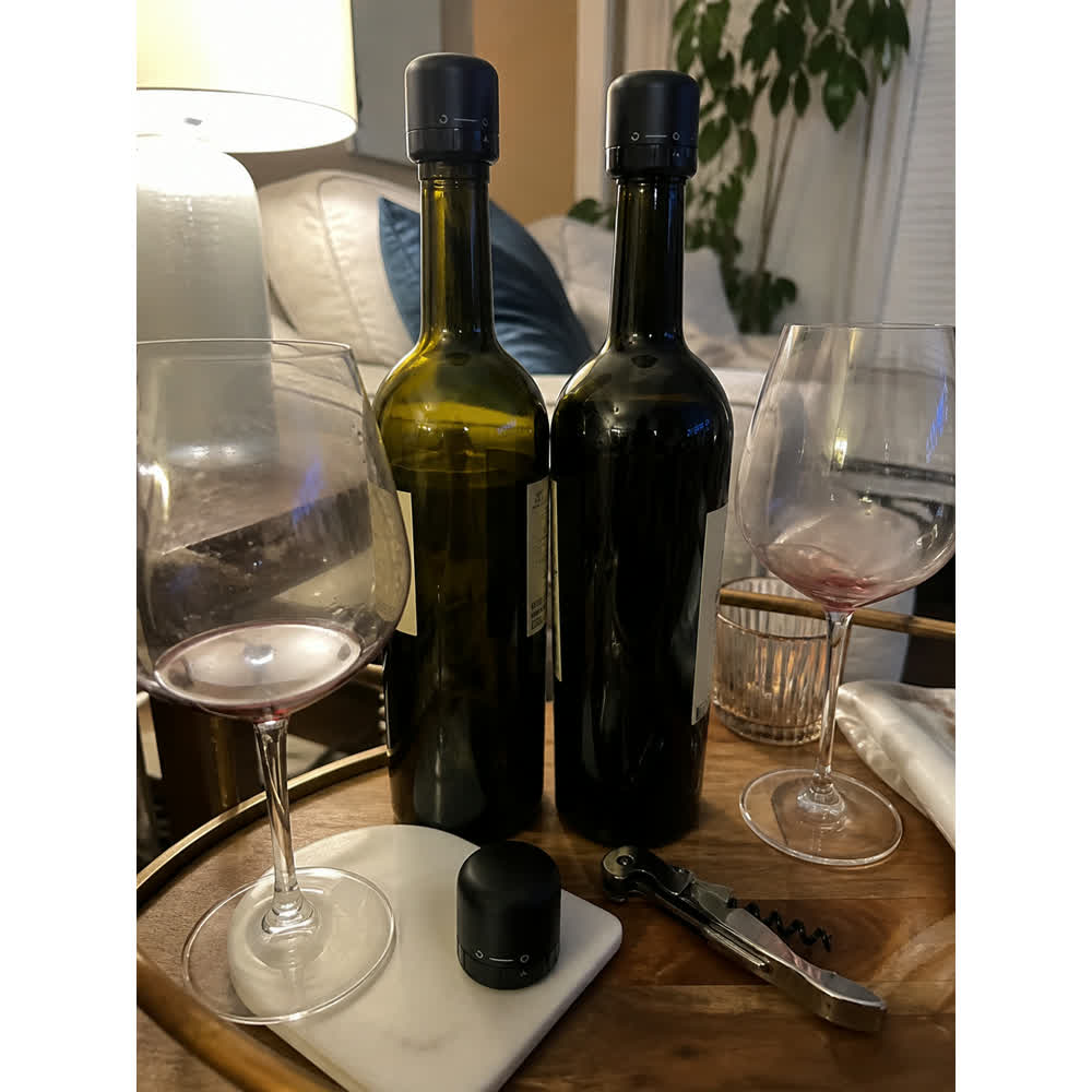 Two opened wine bottles sealed with black wine stoppers on a bar cart