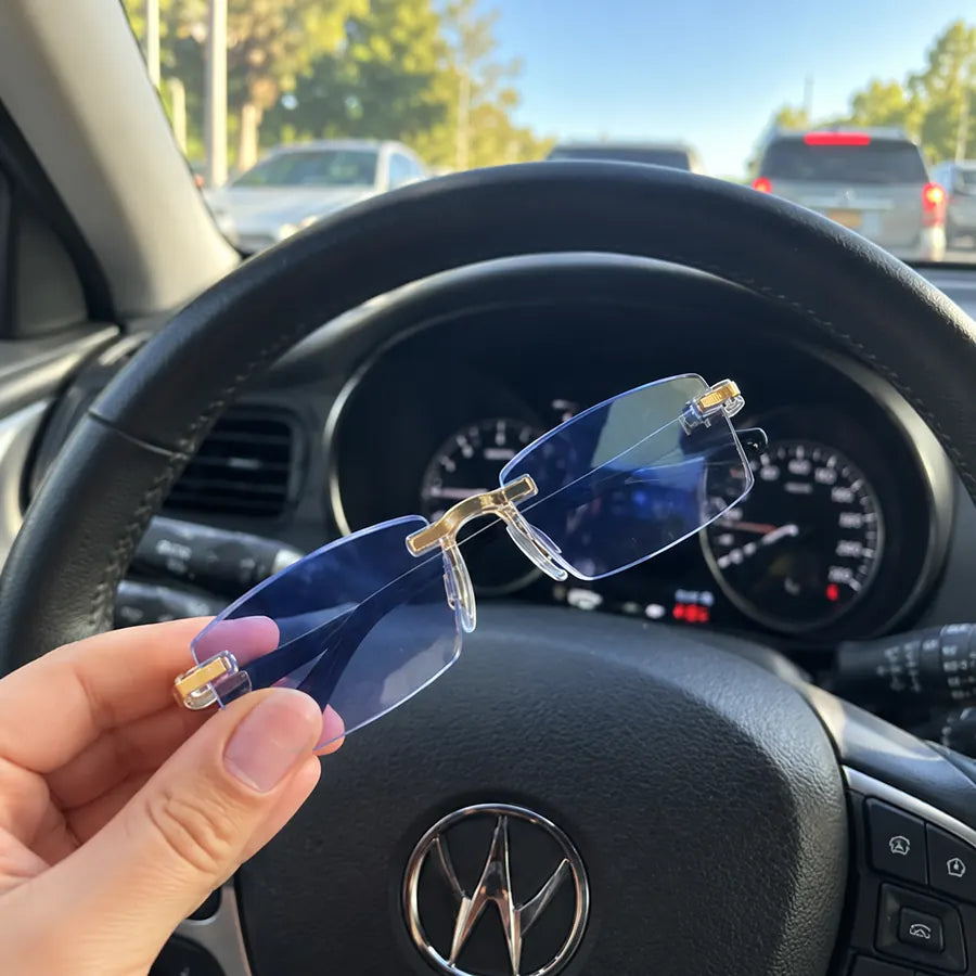 Blue-light rimless glasses held inside a car near the steering wheel